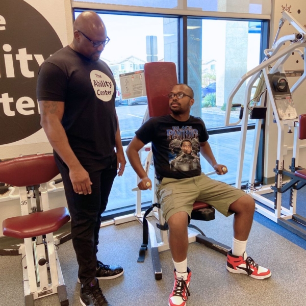 two men in a fitness gym learning how to use weight equipment