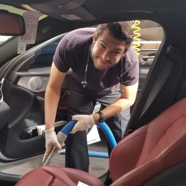 young person vacuuming the interior of a car
