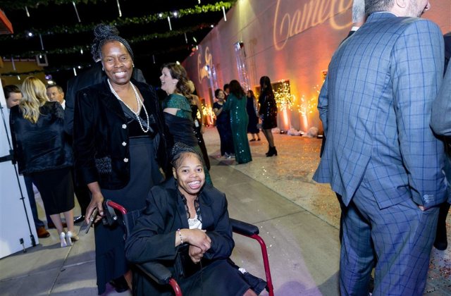 woman pushing another person in a wheel chair at a gala event