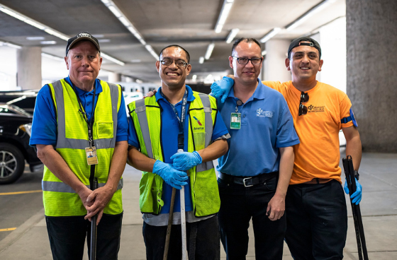 group of 4 people holding brooms standing in a parking garage