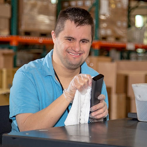 man at job skills training wiping a remote control with a cloth