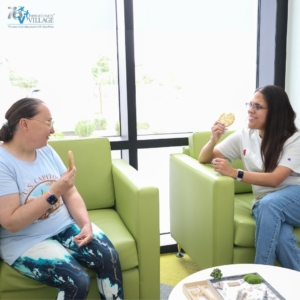 two friends sitting in green chairs eating cookies