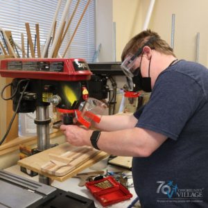 person using a powered drill for a wood arts project