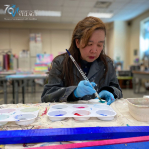 person with a paintbrush dipping it into a paint tray