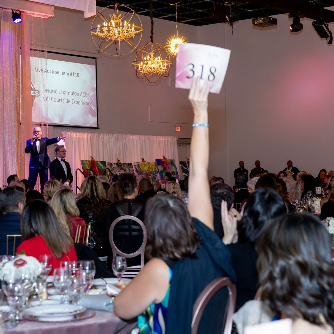 person holding her hand up with a auction bid paper at a charitable event